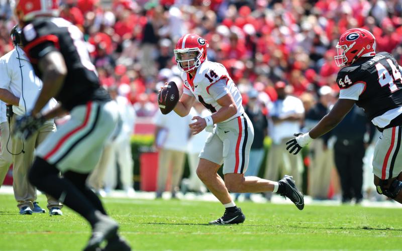 Wade Cheek/The Clayton Tribune.  Gunner Stockton evades pressure from his own Bulldog teammates in Georgia’s spring game last weekend. Stockton led his red team to a 34-17 win over the opposing black team and fellow quarterback Ryan Puglisi.