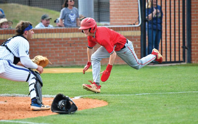 Wade Cheek/The Clayton Tribune. Rabun County pinch-runner Colter Cannon dives into home safely in a play at the plate during Game 1 of Rabun’s playoff series against Bremen on Friday, April 25.