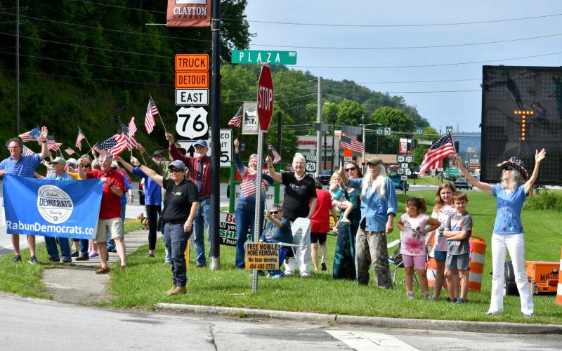 Enoch Autry/The Clayton Tribune.  A group of Rabun County Democrats and others stand on sidewalk near the Food Bank of Northeast Georgia in Clayton as they yell words of support and wave American flags.