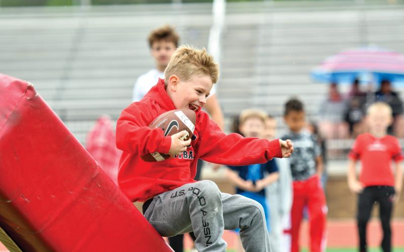 Wade Cheek/The Clayton Tribune. Rabun County football camper Greyson Solary soars into a practice dummy during a running-back drill at this year’s Rabun football kids camp on Saturday, May 10.