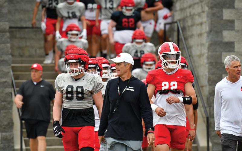 Wade Cheek/The Clayton Tribune. Seniors Ethan Hopper (left) and Ty Truelove (right) join head coach Rance Gillespie (middle) in leading the Wildcats into Frank Snyder Memorial Stadium before Rabun’s spring football game on Friday, May 16.