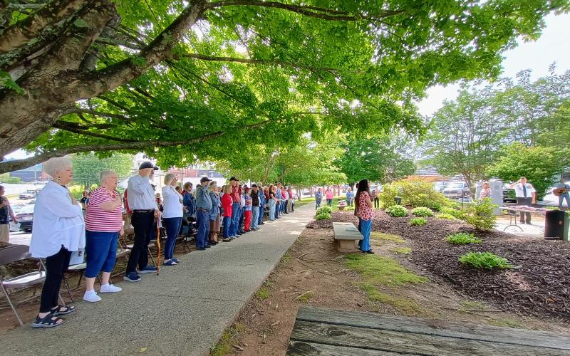 Megan Horn/The Clayton Tribune. A large crowd attended the Memorial Day event held at the Veterans memorial in front of the Rabun County Courthouse Monday. Community members, including many veterans and family members of fallen soldiers, stand for the Pledge of Allegiance and singing of “The Star-Spangled Banner.” Veterans saluted with respect.