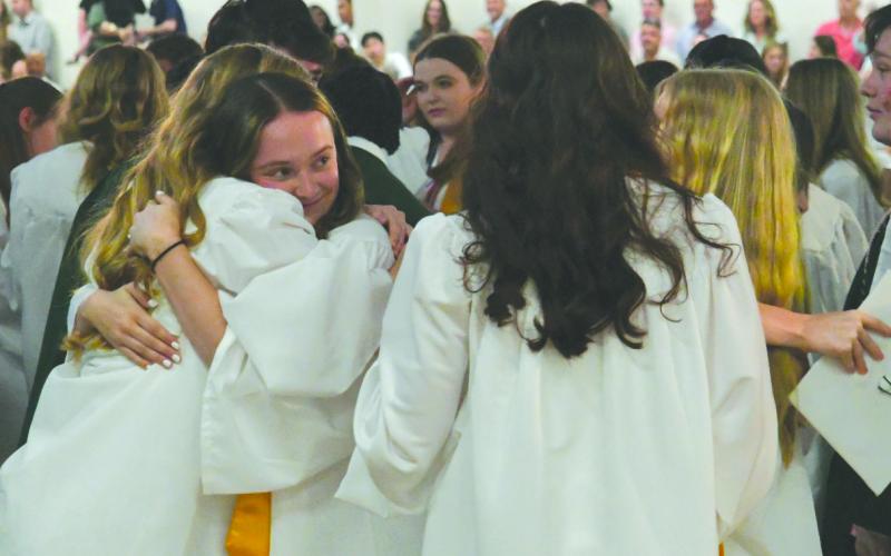 Enoch Autry/The Clayton Tribune. Ava Hamon (left) smiles as she hugs fellow Tallulah Falls graduates at the conclusion of the May 22 graduation ceremony in the Student Activity Center pm the TFS Lower/Middle School Campus.