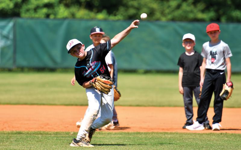 Wade Cheek/The Clayton Tribune. Max Speed fires a throw over to first base during an infield drill at the TFS baseball camp last week.