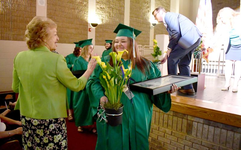 Megan Horn/The Clayton Tribune. 2025 Mountain Education graduate JaLynn Lee Pendrey, right, talks to Mountain Education Faculty Member Joyce Green. Each graduate received a yellow Calla lily donated by Walmart.