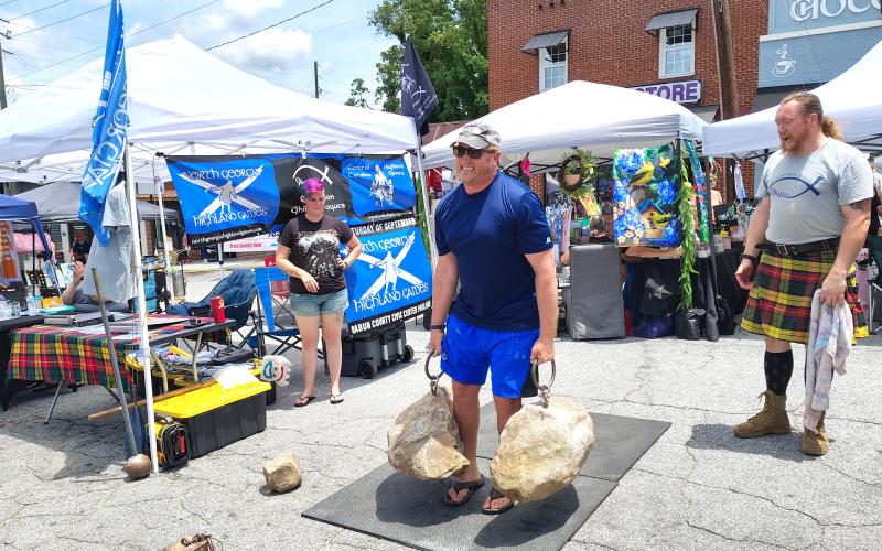 Photo courtesy Conner Horn. Doug Miller (center) lifts heavy rocks during Ramshackle 2025 last weekend as event-goers watch with excitement. Many people attempted the lift throughout the day.