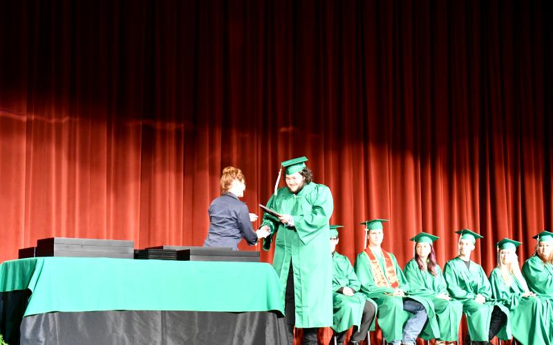 Megan Horn/The Clayton Tribune. Rotary Club of Clayton President Sheryl Webster presents Rotary’s scholarship to 2025 Rabun Mountain Education graduate Johnathan Robert Lee Watts during the May 28 graduation ceremony.