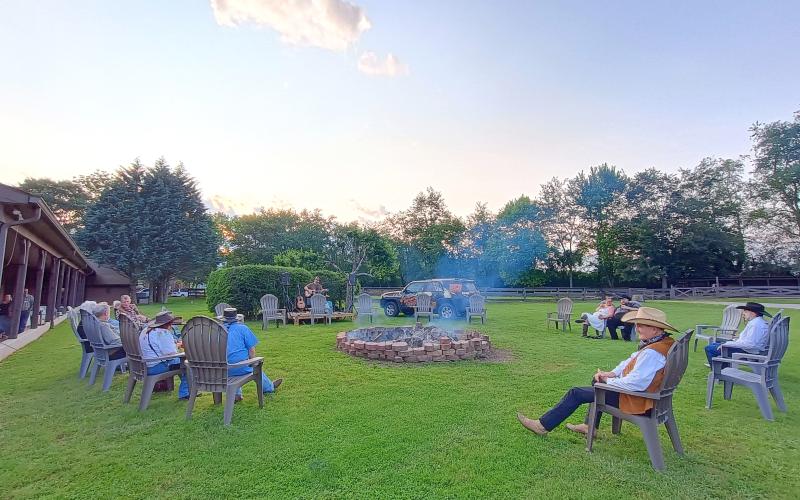 Megan Horn/The Clayton Tribune. Tom Proctor plays music around the campfire during the evening on May 31 following the Forward Rabun/Rabun County Chamber of Commerce member awards. People relax as they listen to music and enjoy the view.