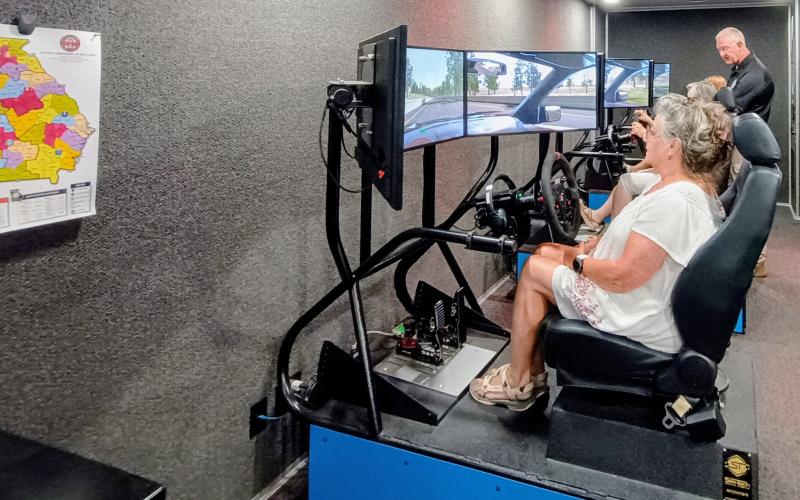 Megan Horn/The Clayton Tribune. Officer Mote with the Georgia Department of Public Safety Motor Carrier Compliance Division instructs Transportation Department employees on driver education safety with a driving simulator. Rabun County Schools held its back to school meeting on Tuesday, July 29, at the Rabun County Board of Education. The driving simulator featured different scenarios that could cause distractions and how to stay safe on the roadway while operating a bus full of children.