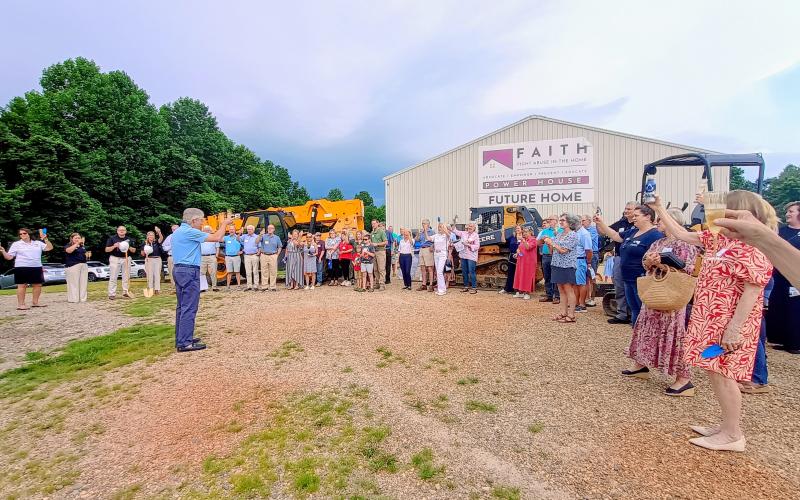 Megan Horn/The Clayton Tribune.  Greg Rhodes, chairman of the F.A.I.T.H. Board of Directors, leads a champagne toast with F.A.I.T.H. employees, community members, donors, local leaders and officials who attended the June 26 groundbreaking of the new Power House Child Advocacy Center and Sexual Assault Center. The group toasted to F.A.I.T.H. in the future.