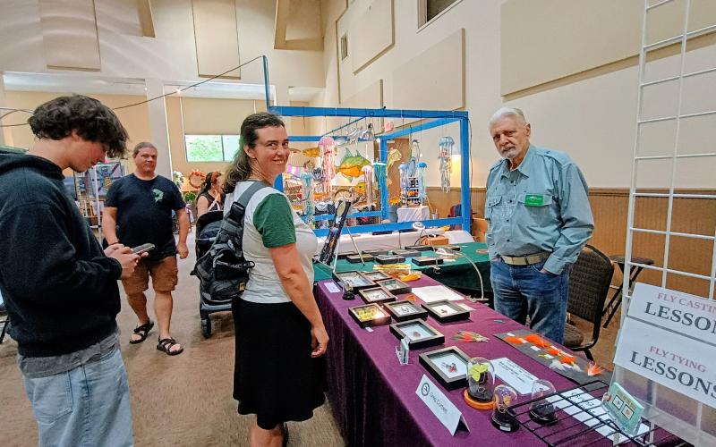 Megan Horn/The Clayton Tribune. Painted Fern Art Festival exhibitor Greg Corbett, right, talks to Joy Fields and Elijah Fields from Portland, Ore., who attended the Painted Fern Art Festival in Clayton last weekend.