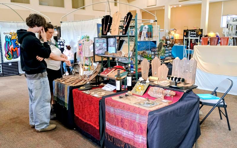 Megan Horn/The Clayton Tribune. Joy Fields and Elijah Fields from Portland, Ore., look at jewelry and copper creations by Brenda Steele during the July 12 and 13 Painted Fern Art Festival, presented by the North Georgia Arts Guild.