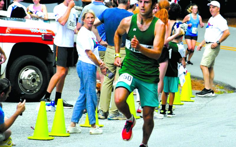 Enoch Autry/The Clayton Tribune. Ben Perrin crosses the finish line as the first overall male in the Rabun Ramble 10K.