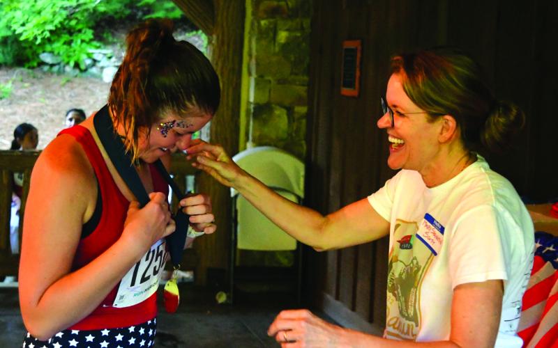 Enoch Autry/The Clayton Tribune. Rabun Ramble Director Molly Shannon Scott presents Autumn Ruhl of Toccoa her medal for winning the female 35-39 bracket.