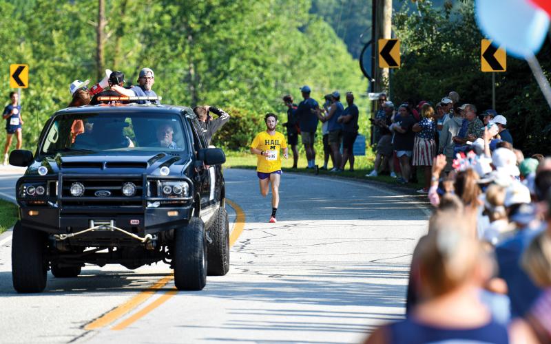 Wade Cheek/The Clayton Tribune. Led by the pace car, Nolan Weisdorfer sprints toward the finish line to repeat as the overall winner of the Lake Burton Fun Run on Saturday, July 5.