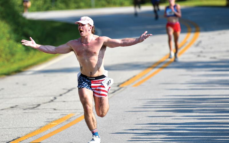 Wade Cheek/The Clayton Tribune. Atlanta resident Brooks Merkle celebrates as he crosses the finish line of the Lake Burton Fun Run.