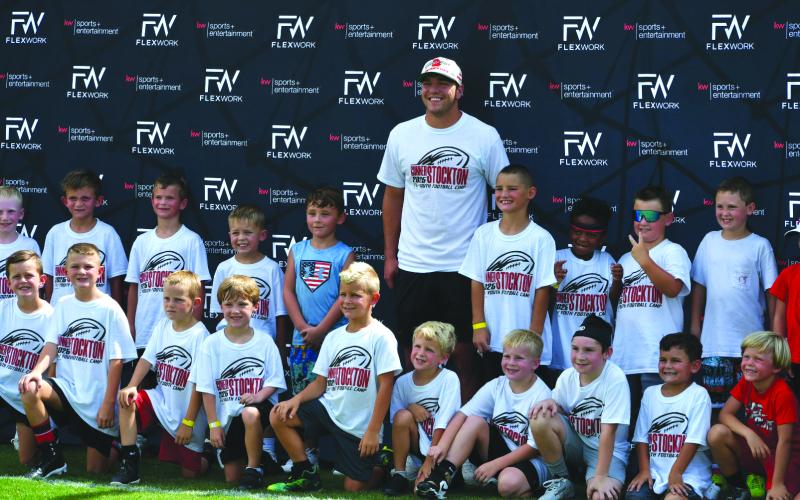 Enoch Autry/The Clayton Tribune. Gunner Stockton poses for a photo with a big group of 6-year-olds at his football camp.