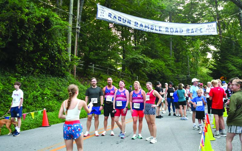 Enoch Autry/The Clayton Tribune. Claire Worley hands the cell phone back after taking a pre-race photo of Stephen Ruhl, Craig Leverett, Tammy Camp, Angie Bowers and Autumn Ruhl. Worley was the second overall finisher in the 5K for the women.