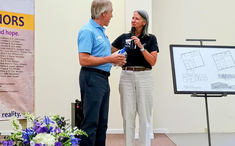 Megan Horn/The Clayton Tribune. Caroline Wallis, executive director of F.A.I.T.H. (right), presents Greg Rhodes, chairman of the F.A.I.T.H. Board of Directors, with a special award on June 26 thanking him for his dedication to the project and all he does for F.A.I.T.H. and the community. To the right, is a rendering of the new facility in Mt. Airy, Ga.