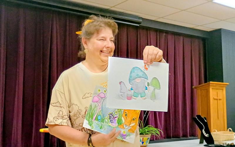 Megan Horn/The Clayton Tribune.  Gretchen Roach displayed her mixed-medium illustrations featuring fairies and gnomes during the Guild’s “Members’ Show and Tell” program July 17. She said her focus is to produce something positive in her creations.