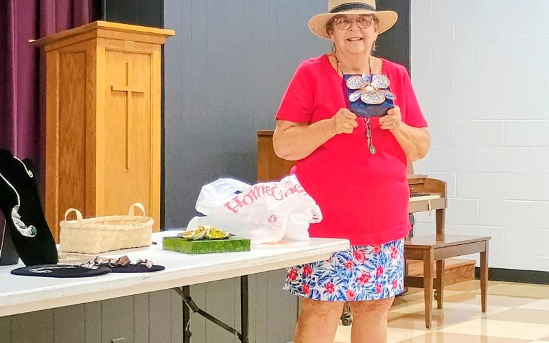 Megan Horn/The Clayton Tribune. Joey Alrich-Burel presents colorful napkin holders she made using oyster shells and muscle shells she collects from restaurants she visits. She showed fellow North Georgia Arts Guild members during the July 17 “Members’ Show and Tell” program.