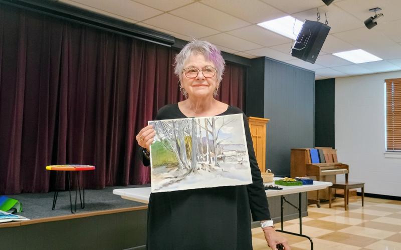 Megan Horn/The Clayton Tribune. Lynn Roe proudly displayed her watercolor paintings at the July 17 North Georgia Arts Guild “Members’ Show and Tell” program. This painting depicts the Oregon Coast where she often spends time with her family.