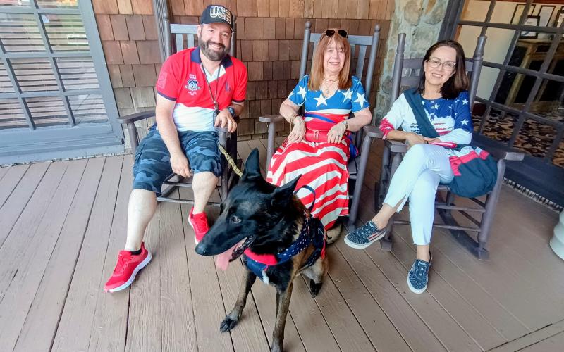 Megan Horn/The Clayton Tribune. Cathy Gomez, Andres Vargas, and Doris Sterling along with dog “Atlas” relax on the porch at The Dillard House during the July 4 annual event.