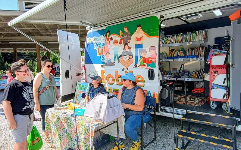 Megan Horn/The Clayton Tribune. The Northeast Georgia Regional Library System Bookmobile was on site at the Rabun County Fuller Center for Housing “Touch-A-Truck” event Saturday, Aug. 16. Pictured are Matthew Ramey, 10, left; Samantha Ramey; Dyana C. Costello Banks, Rabun County Public Library branch manager and librarian; and Jenny Brooks, outreach and Bookmobile manager.