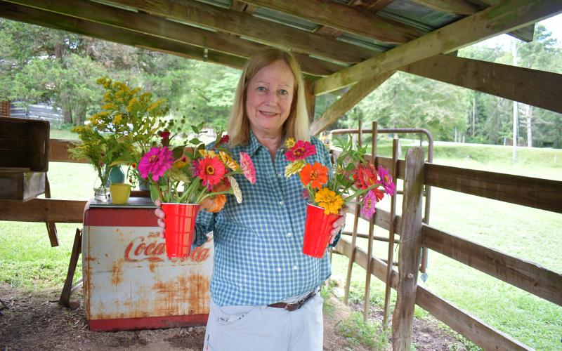 Megan Horn/The Clayton Tribune. Clay Battle is a frequent visitor to Zinnia Happiness Farms and said she loves to give back to breast cancer research. She happily shows off the colorful arrangement she created. The season runs from early July to about mid-October.