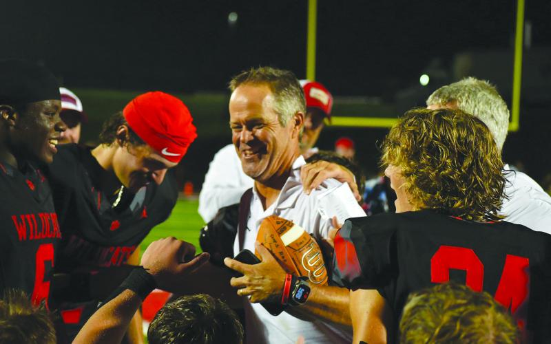 Enoch Autry/The Clayton Tribune. RCHS head coach Rance Gillespie celebrates with his Wildcat football players after receiving a football signed by all the team members. Gillespie, who played for Rabun County in the 1980s, got his first win on Aug. 15 against visiting White County.