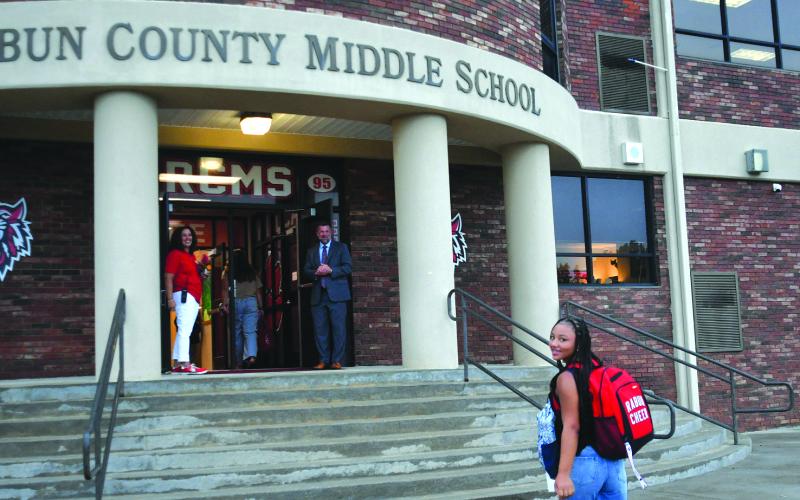 Enoch Autry/The Clayton Tribune. RCMS eighth grader Kinley Burtch walks toward the entrance of the school as Kechara Partin, the middle school principal, and Superintendent Steven Cole get ready to greet her.