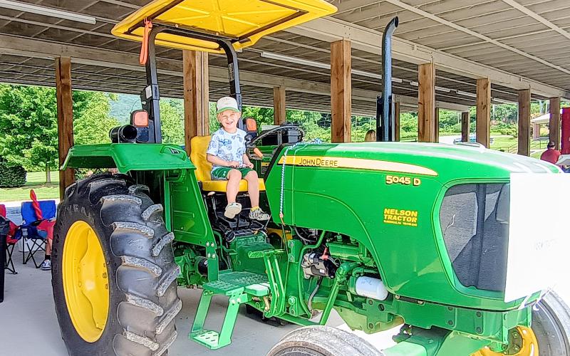 Megan Horn/The Clayton Tribune. Declan Alexander, 4, has fun playing on this farm tractor presented by Marty Franklin during the Aug. 16 “Touch-A-Truck” event. The family-friendly event allowed kids with their families to climb, “touch,” and explore many vehicles that represent our community heroes.