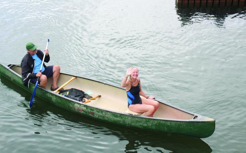 Wesley Branch/The Clayton Tribune. With her husband Steve paddling the boat, Cissy Jackson comes to the boat dock after swimming Lake Rabun in honor of her 60th birthday.