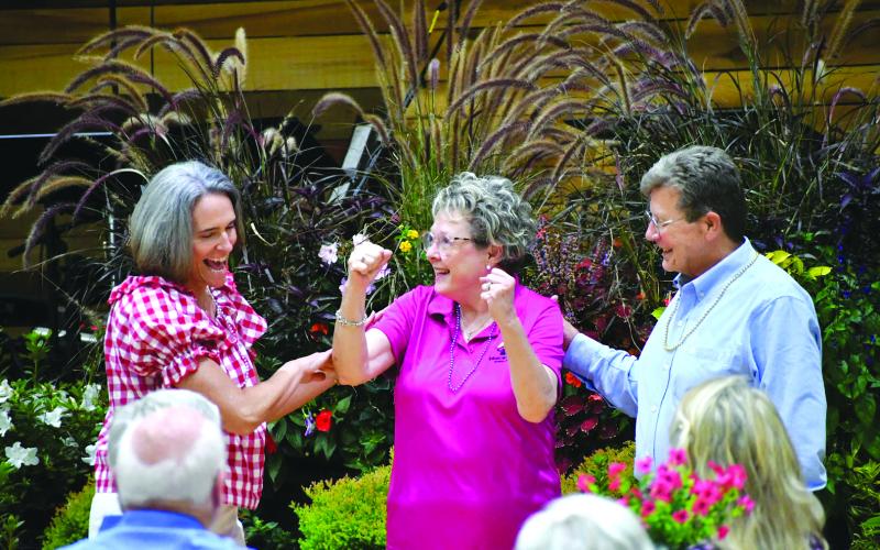 Enoch Autry/The Clayton Tribune.  Elaine Steeley celebrates after winning a prize in the “necklace game” where the “contestants” had to guess heads or tails. If they picked wrong, they lost one of their necklaces they were given at the start of the evening.