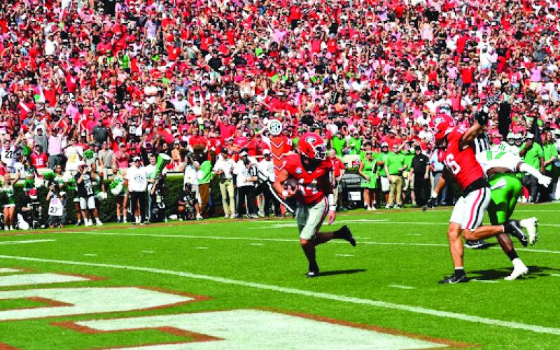 Wesley Branch/The Clayton Tribune. Georgia quarterback Gunner Stockton evades a Marshall defender on his way into the end zone in Georgia’s 45-7 season-opening win on Aug. 30. The former Rabun County standout threw two touchdown passes and ran for two more as the Bulldogs’ No. 1 starting QB.