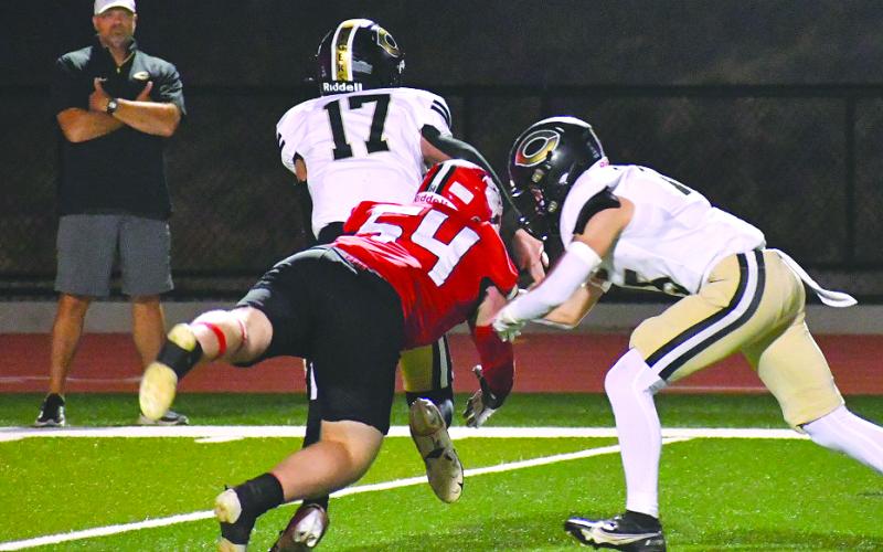 Enoch Autry/The Clayton Tribune. Commerce City School System Superintendent Billy Kirk (far left) watches as Wildcat Ryan Yearwood makes a hit on Commerce quarterback Tate Kirk, the superintendent’s son. The elder Kirk would be ejected from the game in the third quarter. RCHS won 55-28.