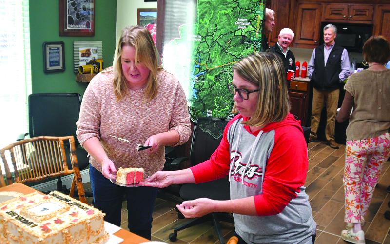 Enoch Autry/The Clayton Tribune. Jim Bleckley stands in the kitchen area of the welcome center talking at the dedication event in his honor on Oct. 24, his birthday. In the foreground, slices are cut from a cake that depicts the plaque that now resides in front of the welcome center on Highway 441 in Clayton.