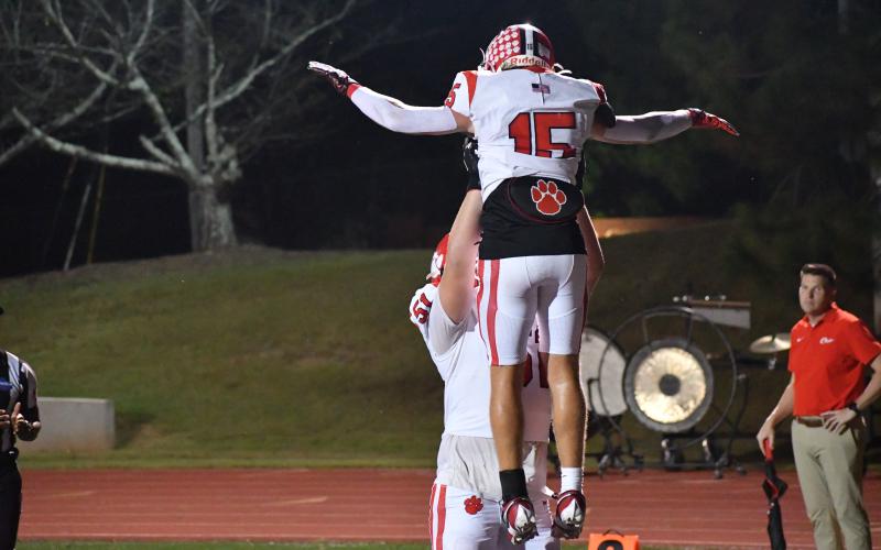 Wesley Branch/The Clayton Tribune. Offensive lineman Skylar Gunn lifts Reid Giles into the air in celebration after a touchdown versus PCA.