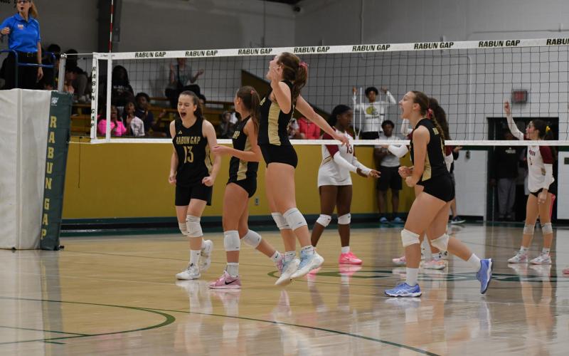 Wesley Branch/The Clayton Tribune. Rabun Gap players celebrate after a 3-2 playoff victory over Cannon on Oct. 10. The win marked the first playoff win for head volleyball coach Zoe Kennedy, and the Eagles’ senior class.