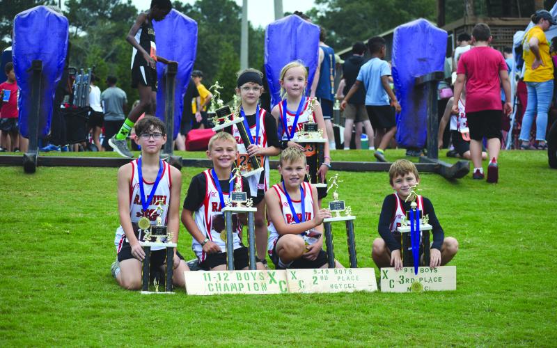 Submitted Photo. Rabun County high-point top-five champions are Caiden Wood, Kai Hanifan-Wagner, Owen Mosely, Keegan Hanifan-Wagner, Nora Webb and Opal Aker sit on the grass with their trophies at the concluson of the district championship at Athens Christian School.