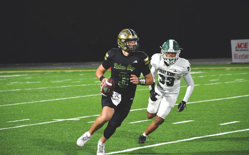 Wesley Branch/The Clayton Tribune. Rabun Gap quarterback Grayson Clary looks downfield for a receiver while escaping a Christ School defender in the Eagles’ 64-7 win over the Greenies on Nov. 6. Clary threw for two touchdowns in the game.