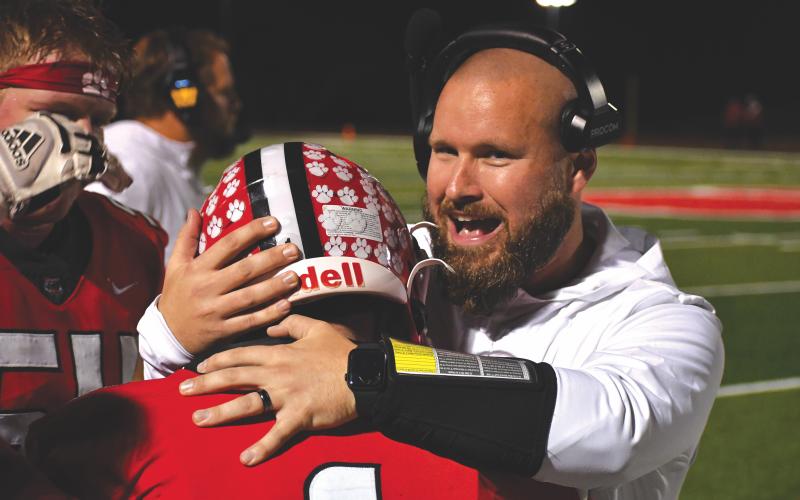 Wesley Branch/The Clayton Tribune. Rabun County running backs coach Clay Worley hugs Lake Evans after the senior dashes down the visitors’ sideline for a 46-yard touchdown on Nov. 21. The Wildcats head to Pepperell for the Elite Eight Friday.