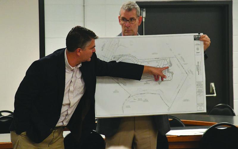 Enoch Autry/The Clayton Tribune. With Gary Hammond Jr., developer/owner of Landbridge Development holding the rendering, Matt Kriete of Engineering, Survey and Services, Inc., points out the location where the parking spots would go on the property at the future Peaks of Clayton housing project.