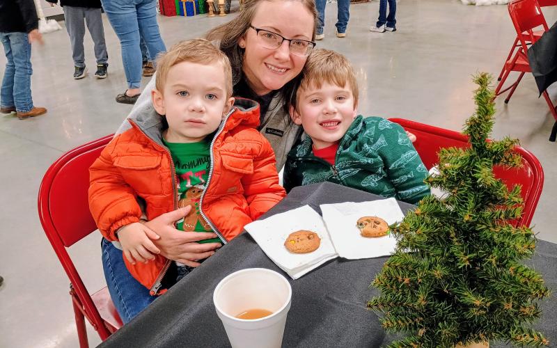 Megan Horn/The Clayton Tribune. Camden Speed, 2; Courtney Speed; and Calum Speed, 5, enjoy festive holiday snacks at the Rabun County Schools AgriCenter Dec. 4.
