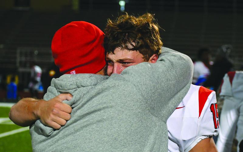 Enoch Autry/The Clayton Tribune. Rabun County senior Reid Giles sheds a tear during a hug with assistant coach Clay Worley on the field after the Wildcats lose to Pepperell in the Elite Eight in Lindale the day after Thanksgiving.