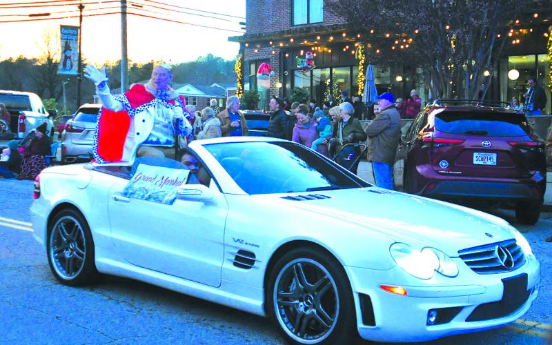 Enoch Autry/The Clayton Tribune. Wearing a king’s crown, Christmas Parade Grand Marshal Tony Penrose says hello to those who gathered along the sidewalk.