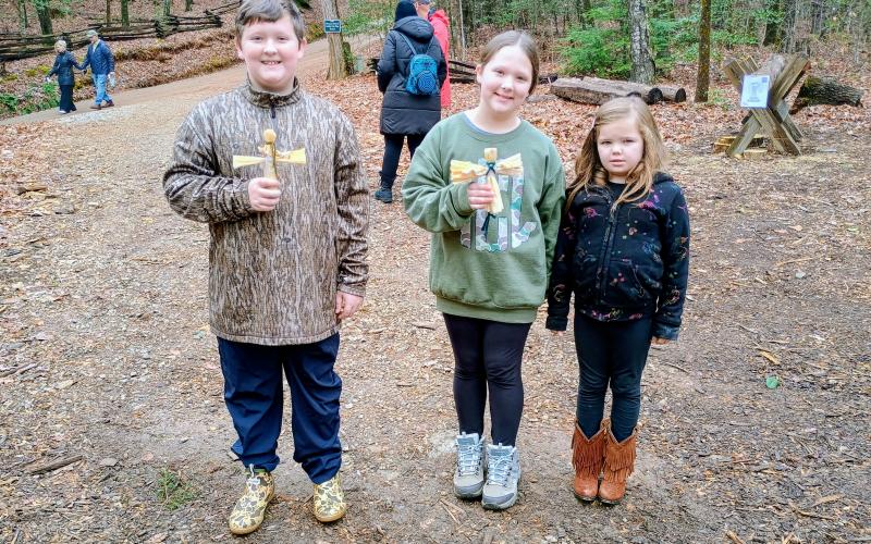 Megan Horn/The Clayton Tribune. Bentley Conner, 10; Ava Conner, 9; and Harper Mashburn, 6, enjoy their time at “A Foxfire Christmas” last weekend. The kids are holding corn husk dolls, one of many crafts made during the event.