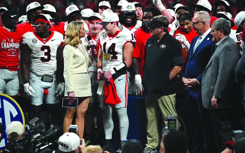 Keith Barlow/CNI News Service. Holding his MVP trophy with his teammates and head coach Kirby Smart on the stage with him, Georgia quarterback Gunner Stockton answers questions from Laura Rutledge after the Bulldogs’ 28-7 win.