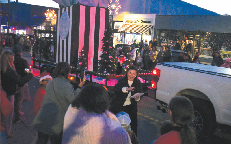 Enoch Autry/The Clayton Tribune. Madison’s on Main won “Best Overall Float” for its giant shopping bag that was among the entries that rolled down Clayton’s Main Street for the annual Christmas Parade. In the background is the business that is located at 41 Main Street. Thousands attended the Dec. 6 event with lighted floats.