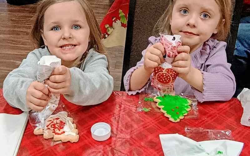 Megan Horn/The Clayton Tribune. Waverly Whitmire, 3, and Violet Whitmire, 5, happily decorate Christmas cookies during a “Mountain City Christmas” on Thursday, Dec. 18. Party-goers also enjoyed live music by the band Blue Ridge Lonesome, popcorn, hot chocolate, cider, and many sweet treats and snacks.